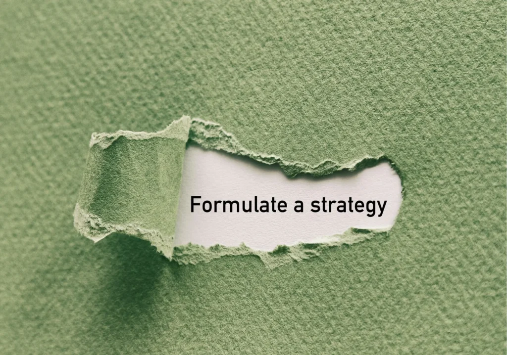 A green sheet of paper with a section peeled back to reveal the phrase "formulate a strategy"
