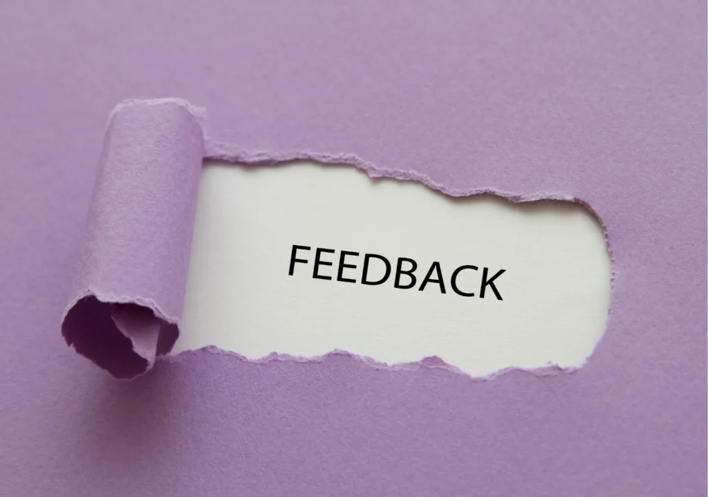 A purple sheet of paper with a section peeled back to display the word "feedback"