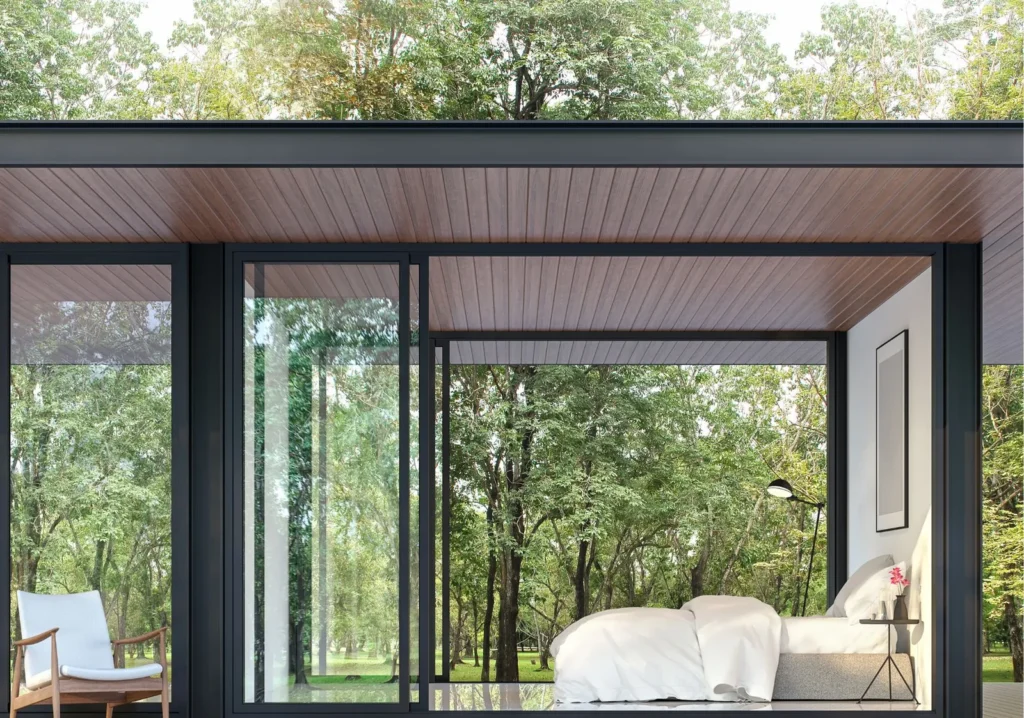 Bedroom with large windows surrounded by trees