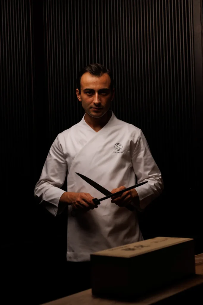 Chef holding knives in the kitchen at Omasava