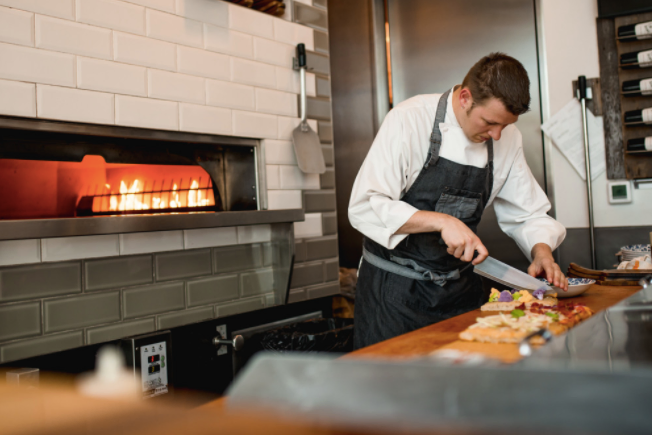 Chef preparing food by the oven at The Bakery at Grappino