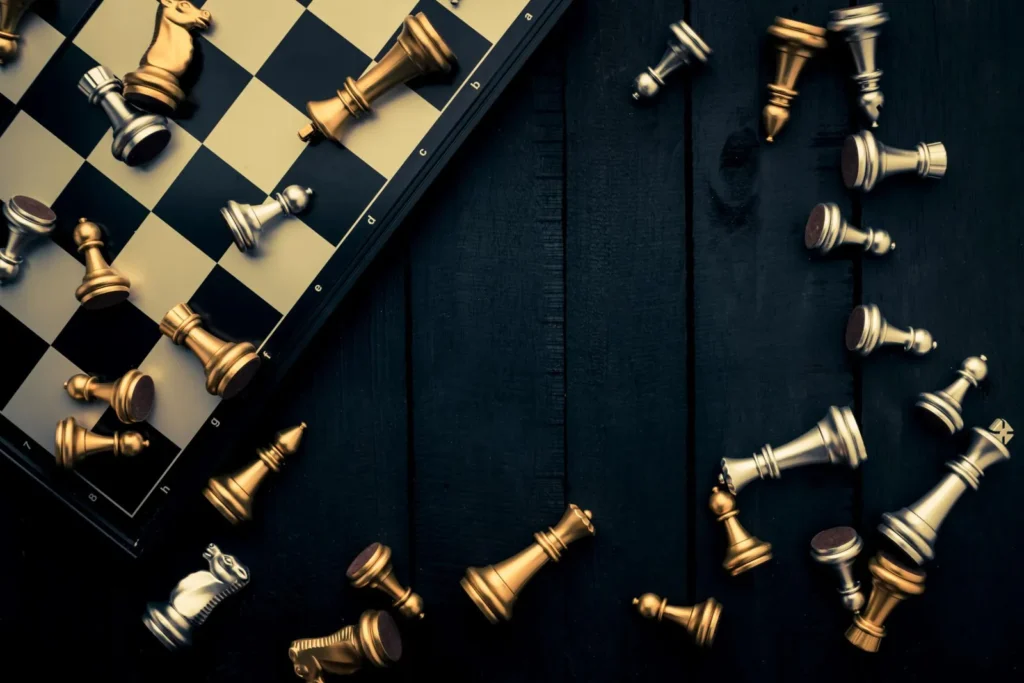 Chessboard with scattered gold and black chess pieces