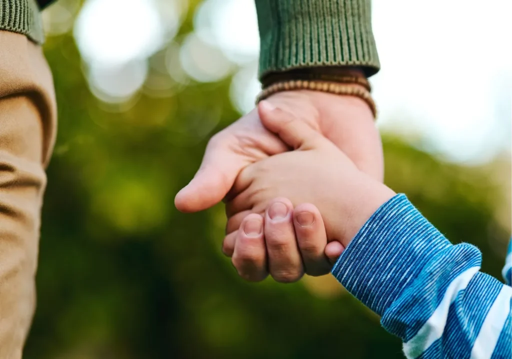 Close up of man holding hands with young boy