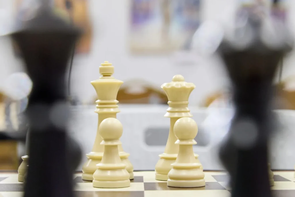 Close-up of white chess pieces facing black pieces on a chessboard