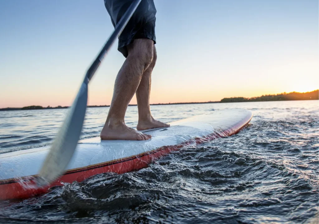 Close up view of man's legs on a paddle board in the water