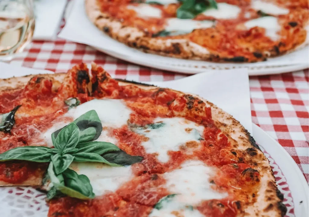 Close up view of two margarita pizzas on a red and white checkered tablecloth