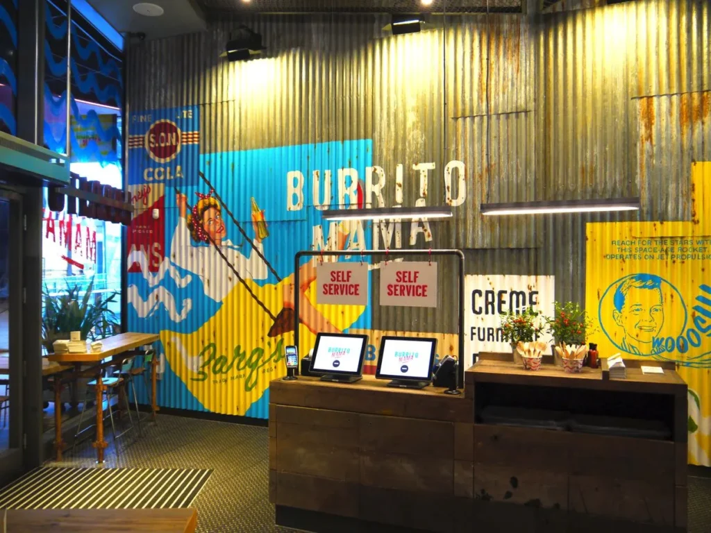 Colorful order counter with self-service kiosks at Crazy King Burrito