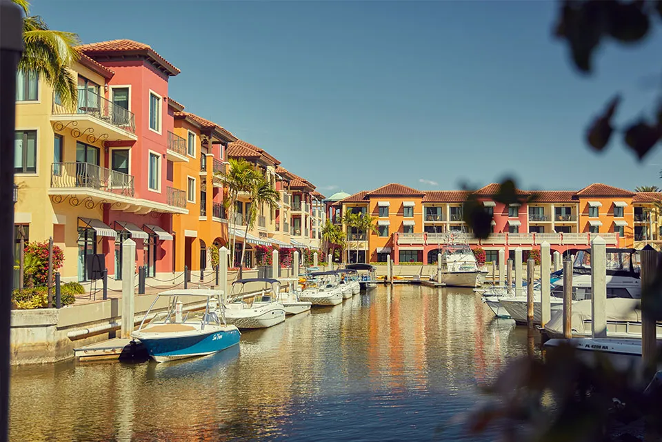 Colorful Venetian Village shops along a Naples canal with docked boats