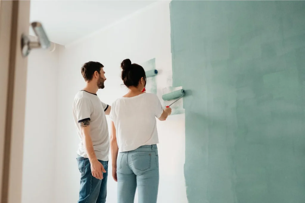 Couple painting wall a green color