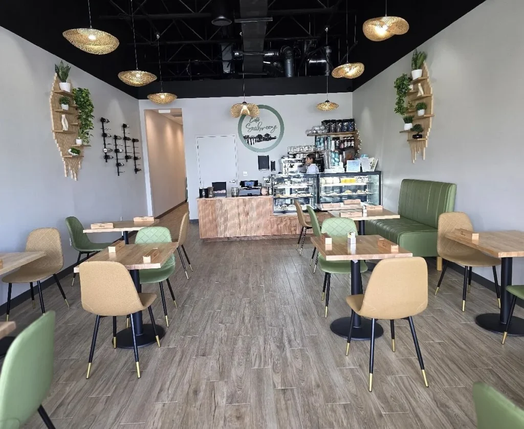 Dining area with green chairs and hanging plants at Cafe Seabreeze
