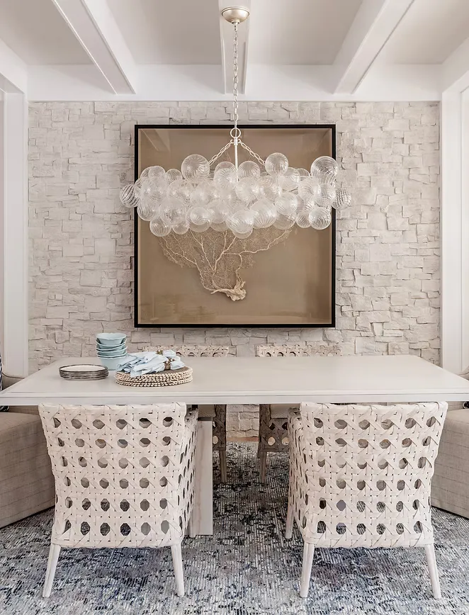 Dining nook with woven chairs and glass chandelier by Abodeable Home