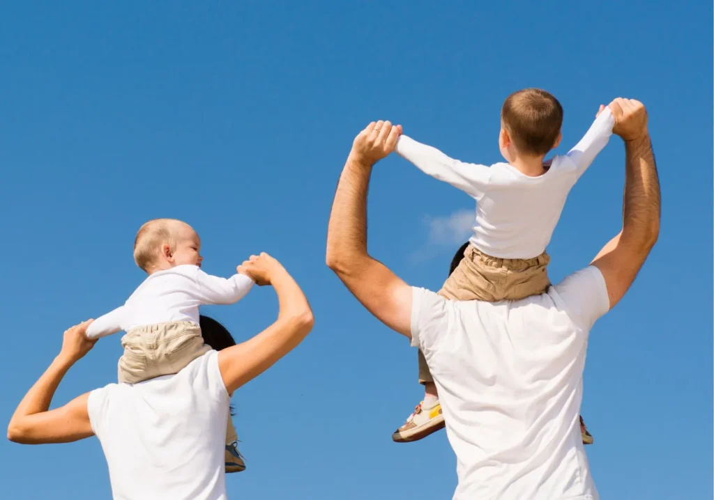From the back, mom and dad both holding a child on their shoulders