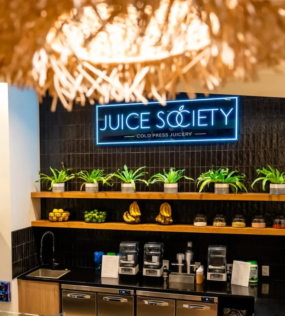 Juice Society counter with neon sign and fresh produce