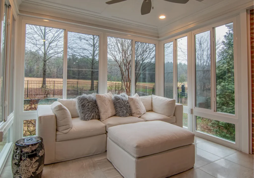 Living room couch and ottoman with large windows behind it