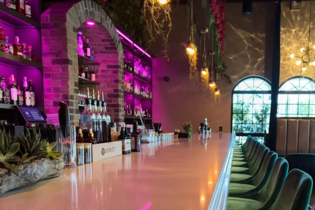 Long bar with pink lighting at District in Naples