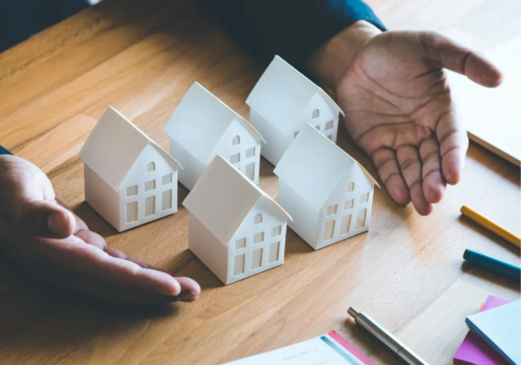Man showing 5 white miniature home models on desktop
