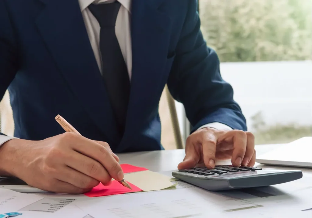 Man using calculator and writing figures