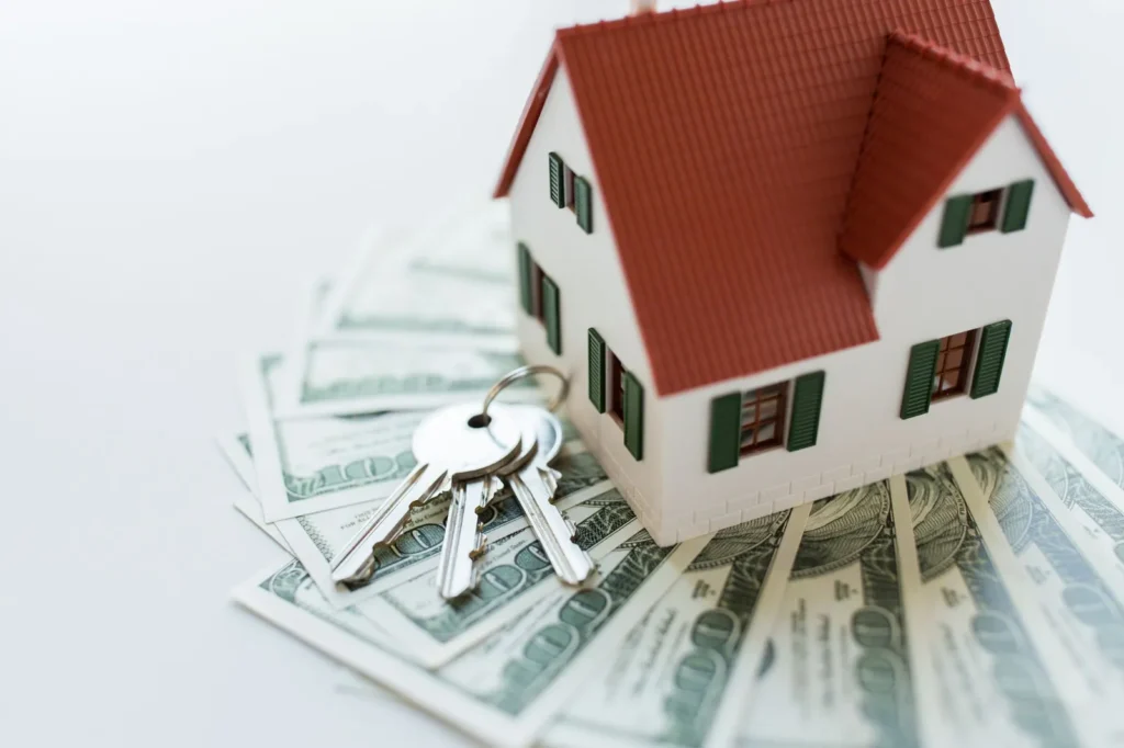 Model house and keys on a pile of cash representing closing costs