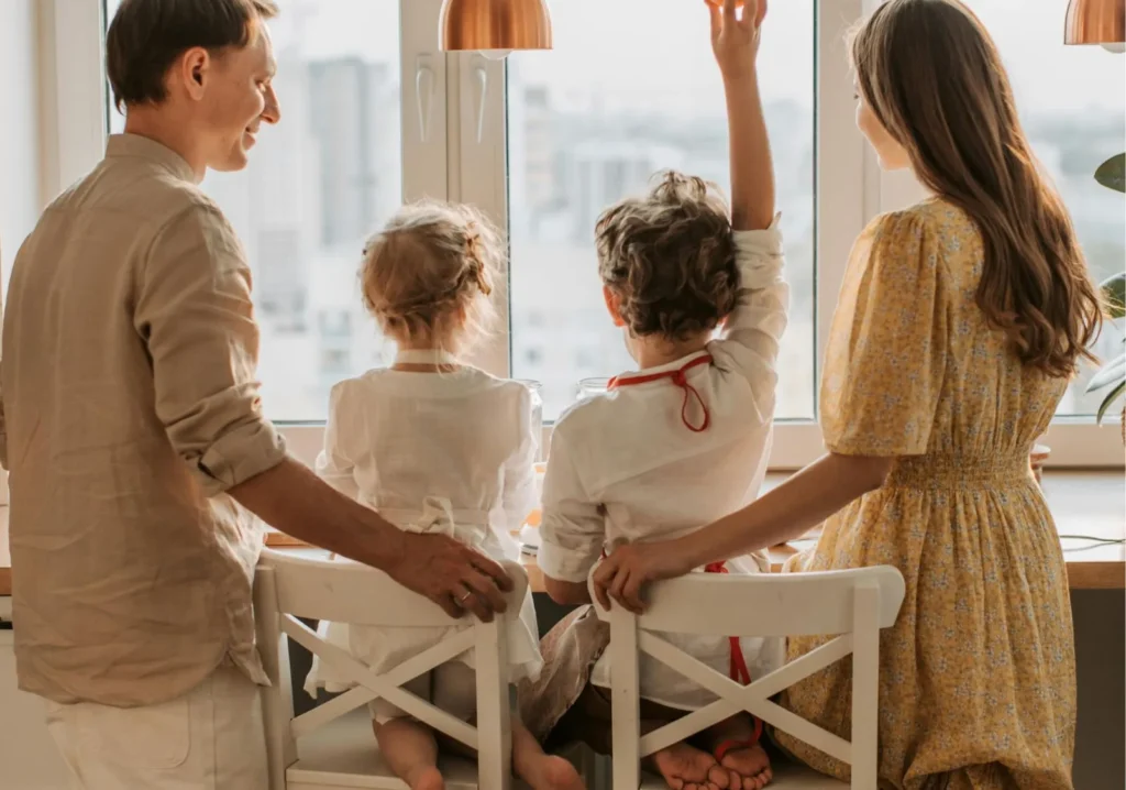 Mom, dad and 2 children looking out a window