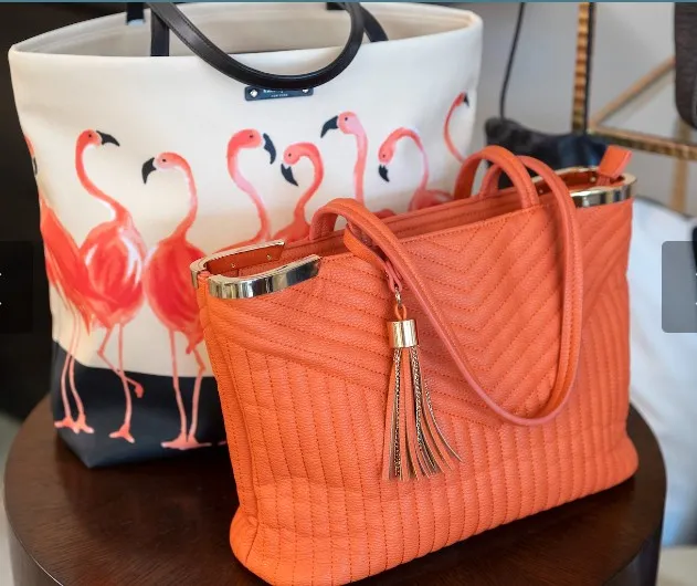 One white purse with pink flamingos and one coral purse