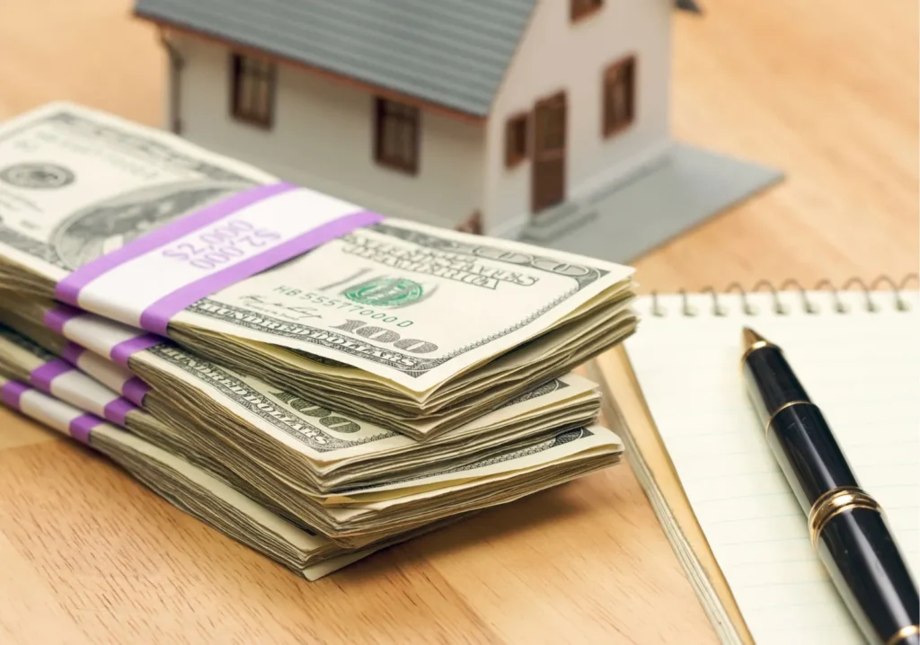 Pile of cash next to a notebook and pen