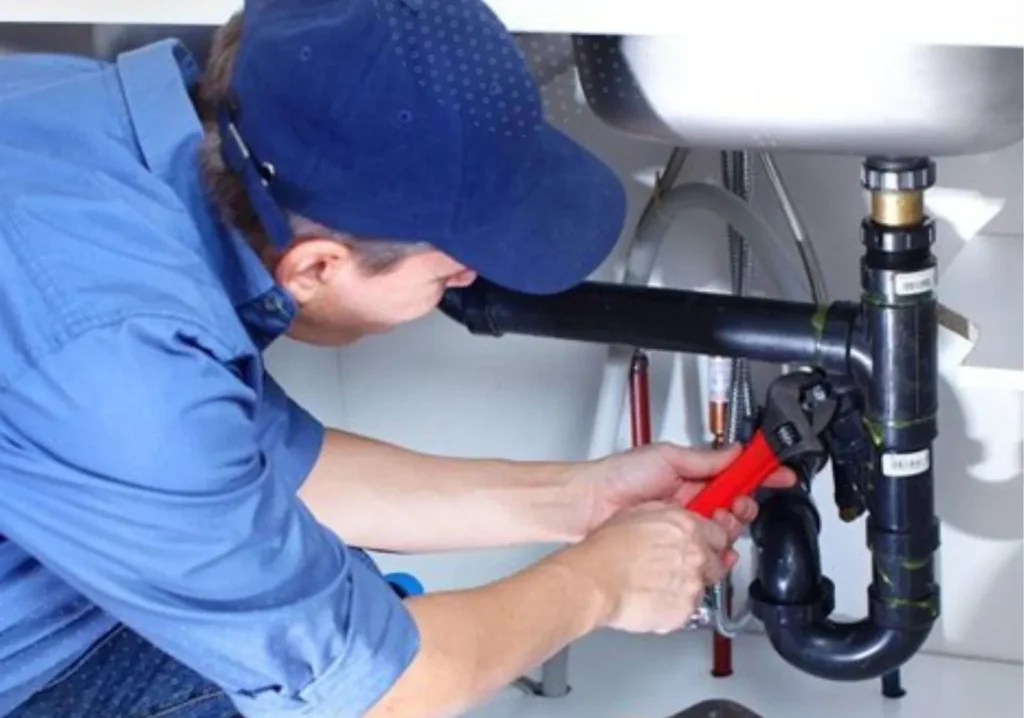 Plumber repairing pipes under a sink
