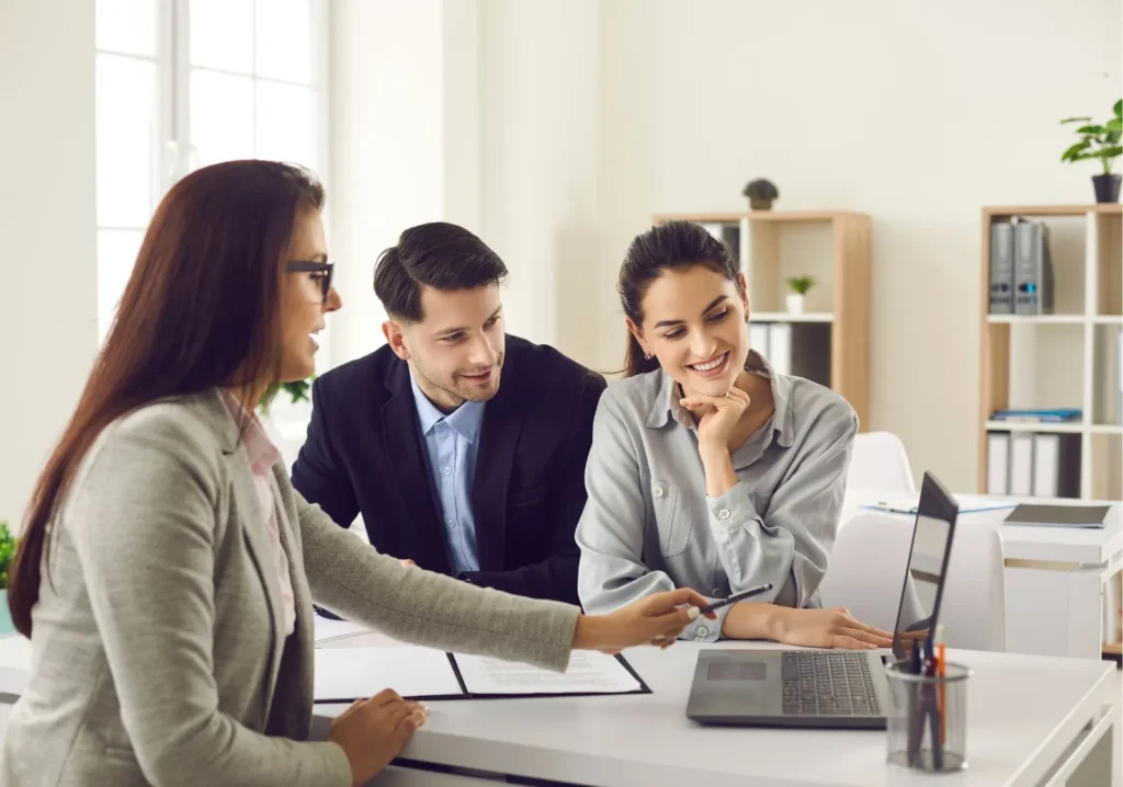 Real estate agent showing couple information on a laptop