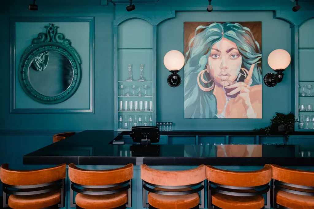 Teal bar with mural and leather stools at The Bohemian