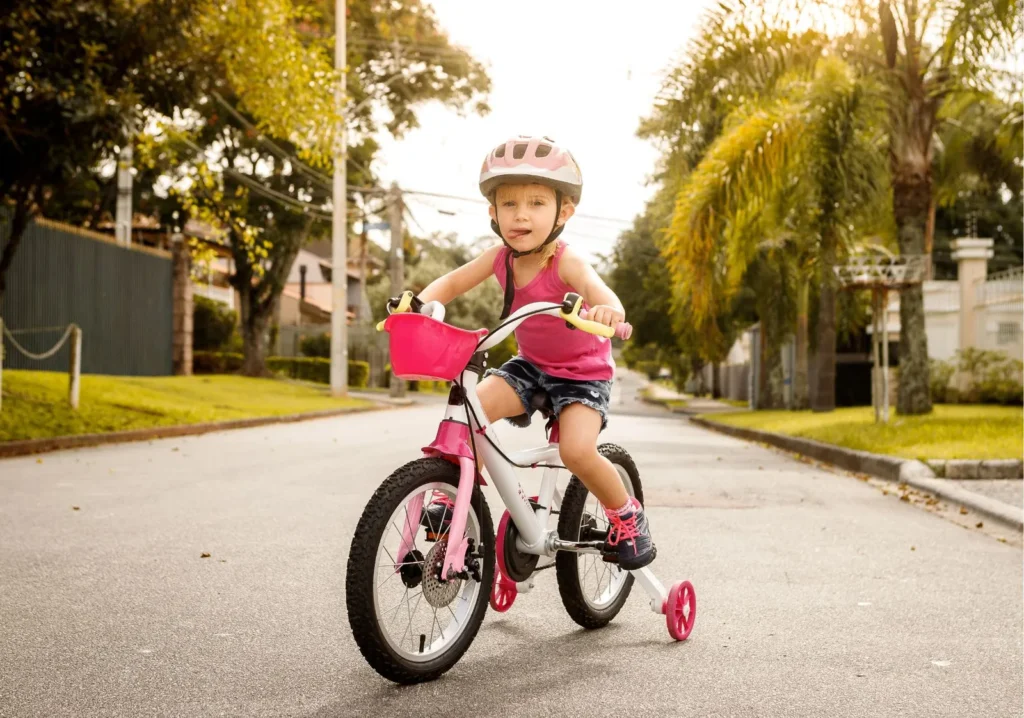 Toddler riding a bike with training wheels in the street