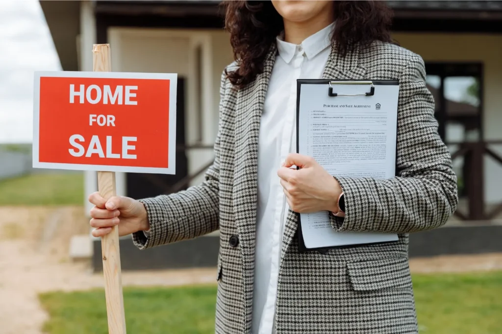 Woman holding home for sale sign