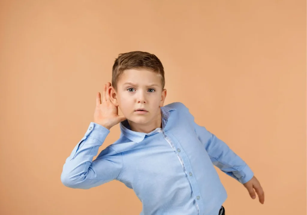 Young boy with hand to ear listening